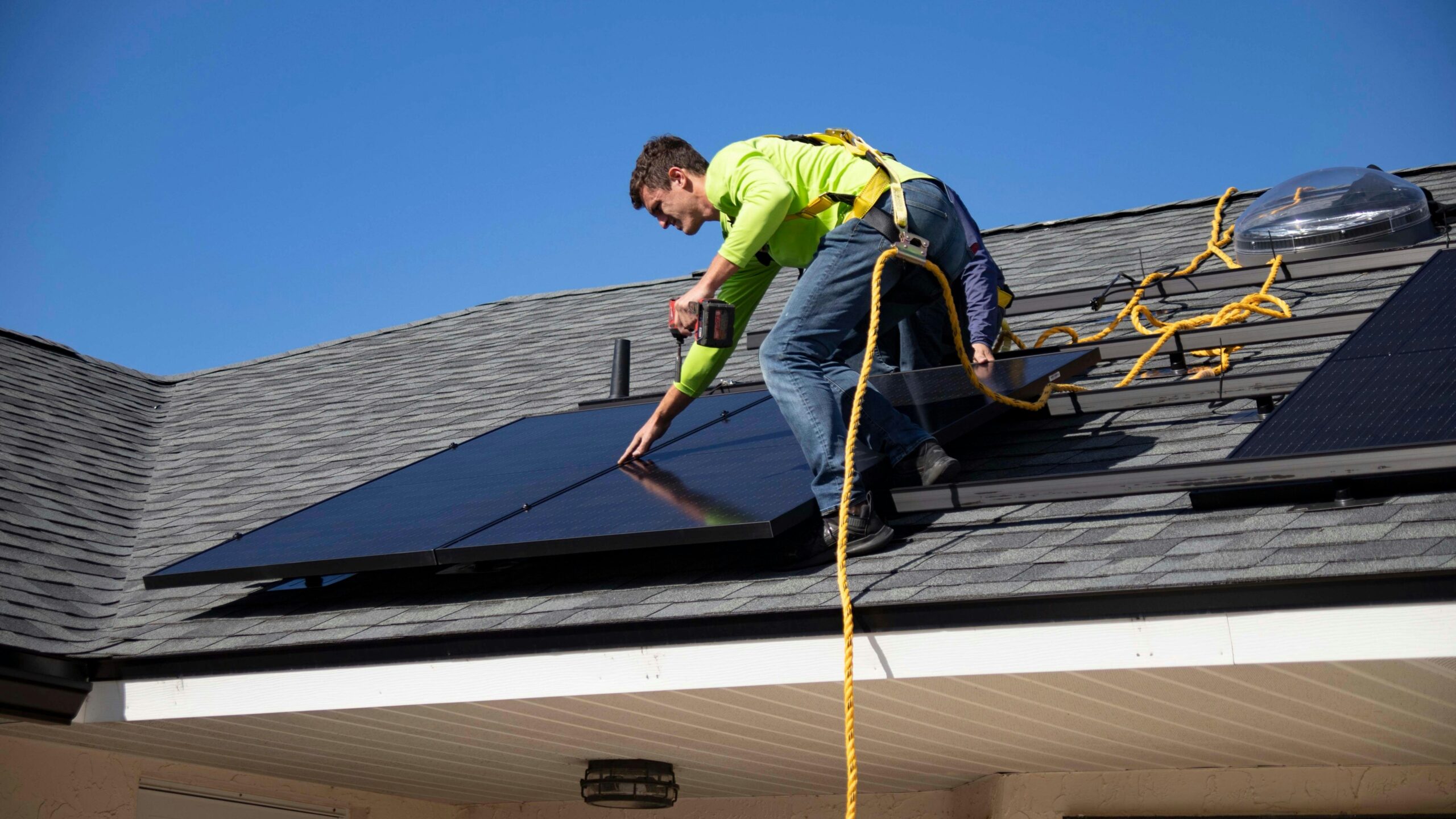Un homme est sur un toit, en train d'installer des panneaux solaires